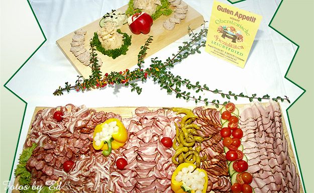 Aufschnittplatte mit Wurst- und Fleischspezialitäten, dekoriert mit Gemüse und Paprika.